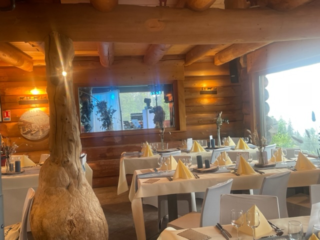 tables dressées dans le restaurant Le Poyet Aux Rousses avec une ambiance bois et vue sur l'extérieur boisée