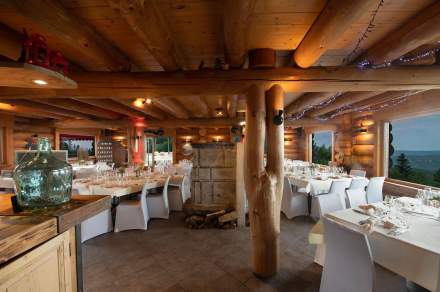 tables dressées dans le restaurant Le Poyet Aux Rousses avec une ambiance bois et vue sur l'extérieur boisée