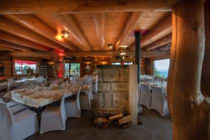 tables dressées dans le restaurant Le Poyet Aux Rousses avec une ambiance bois et vue sur l'extérieur boisée